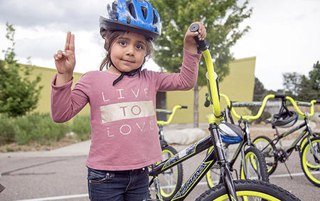 girl in peace sign while holding her bike